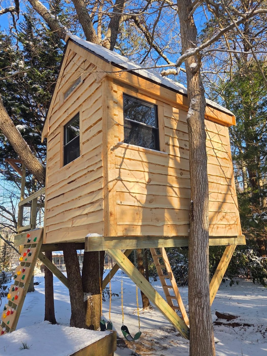 Finished elevated enclosed treehouse cabin with windows and cedar siding