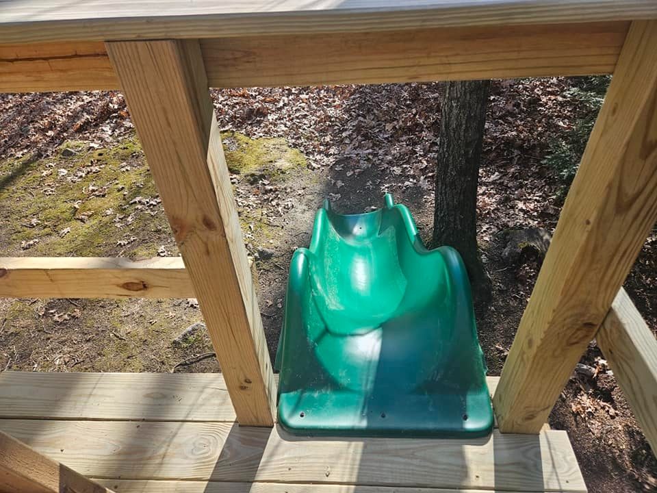 Green slide attached to an elevated treehouse platform