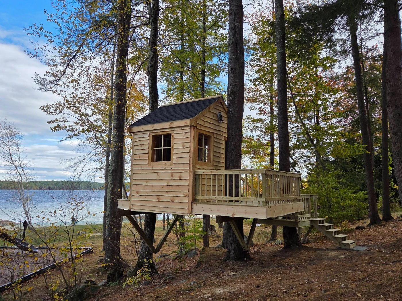 Open-air custom treehouse near the water with deck and railings