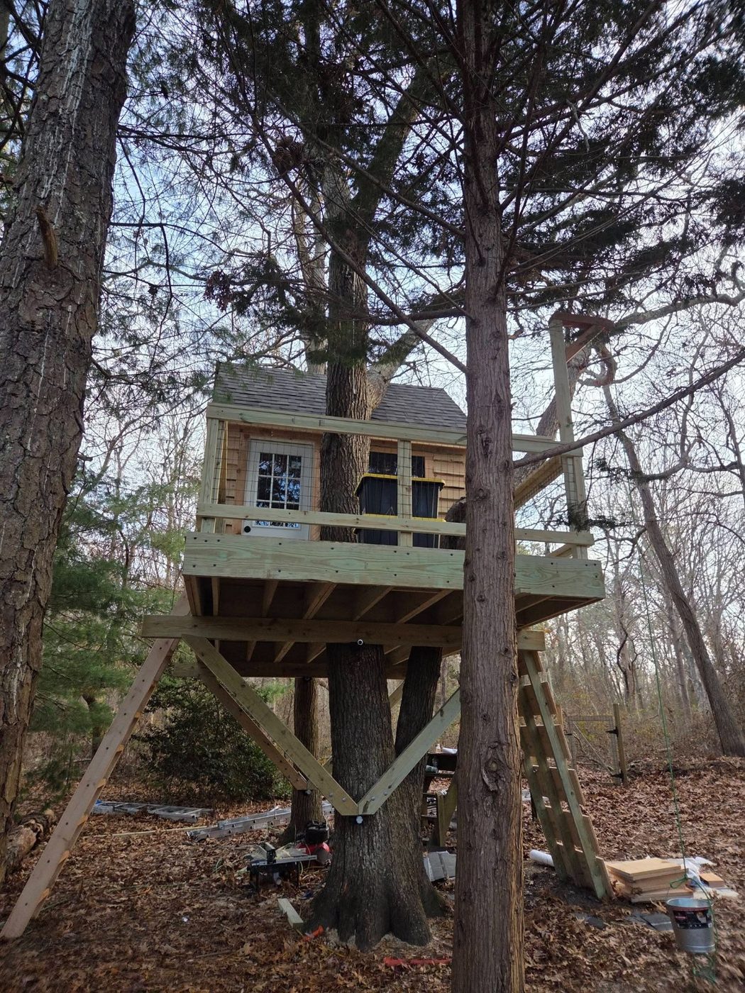 Treehouse with wire fence railing in wooded backyard